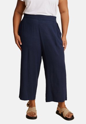 Pantalons larges bleu marine en tissu léger avec une surface texturée. Dotés d'une taille élastique et d'une coupe décontractée.