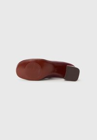 Scarpa con tacco alto marrone, con una finitura liscia, punta arrotondata e suola texturizzata. Il tacco è quadrato e piatto, per un maggiore stabilità.