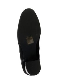 Semelle de chaussure noire avec une finition lisse, présentant un talon bas et une étiquette d'entretien embossée avec des symboles. Le matériau semble durable et flexible.