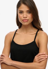 Top senza maniche nero con spalline sottili, caratterizzato da un collo rotondo e una texture morbida e liscia, progettato per comfort e abbigliamento casual.
