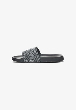 Sandal in gomma nera con una tracolla testurizzata che presenta un motivo floreale bianco. Suola piatta e finitura liscia e opaca.