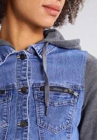 Denim jacket with gray hoodie, snap buttons, and a zippered chest pocket. Features blue denim fabric with distressed texture and gray accents.