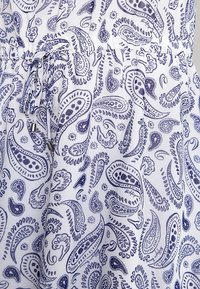 Tejido blanco con una cintura elástica y un cordón, estampado con un denso patrón de paisley azul marino.