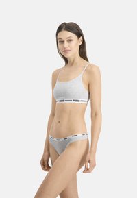 Ensemble bralette et bikini en coton gris avec des bretelles fines et une bande noire arborant le logo "PUMA" dans un style athlétique. Texture lisse, design minimal.