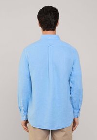 Camicia a maniche lunghe di colore azzurro chiaro in misto lino. Presenta un colletto a camicia, una piega sul retro e polsini con bottoni. Texture liscia.