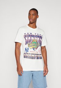 Balta medvilninė marškinė su spalvinga grafika, kurioje užrašyta "NEW YORK YANKEES 1996 METŲ PASAULIO ČEMPIONATAS" ir beisbolo motyvais.