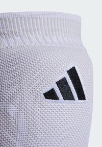 Witte sportkous van textuur gebreid materiaal, met een zwart Adidas-logo als accent aan de zijkant.