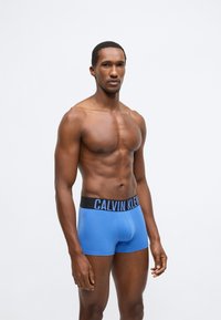Μπλε βαμβακερά ανδρικά εσώρουχα boxer με μαύρη ελαστική μέση με την επιγραφή "CALVIN KLEIN" σε λευκό, εφαρμοστή εφαρμογή, λεία υφή.