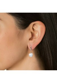 Orecchini a cerchio in argento caratterizzati da un elegante pendente in perla bianca, decorati con dettagli intricati sugli accenti metallici.
