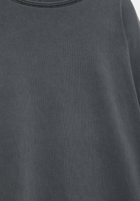 Grå bomulds-sweatshirt med en blød, tekstureret overflade. Har rund halsudskæring, let løs pasform og diskret syningsdetalje omkring kraven.