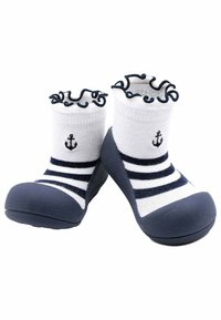 Zapato azul marino con diseño de calcetín a rayas blancas y azules marinos. Presenta un borde rizado y un detalle de ancla bordado en el calcetín. Material suave.