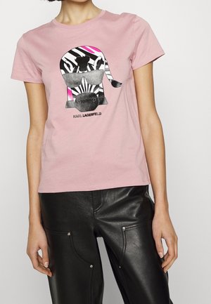 Vaaleanpunainen puuvillapaita, jossa on graafinen kuva auringonsuojalasillisen seepian, abstrakteja kuvioita, lyhyet hihat ja pyöreä kaula-aukko.