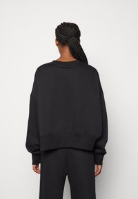 Svart oversized sweatshirt med sänkt axel, ribbade ärmslut och rundad halsringning. Snyggt tyg med en avslappnad passform och croppad nederkant.