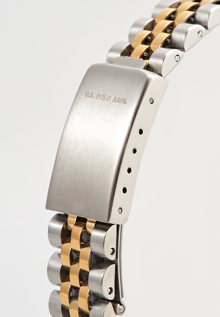 Silberne und goldene Metallarmbandverschluss mit "U.S. Polo Assn." auf der gebürsteten Metalloberfläche eingraviert.