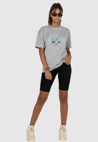 Gray cotton t-shirt with blue graphic text, paired with black biking shorts and beige high-top sneakers. Minimalistic design, short sleeves.