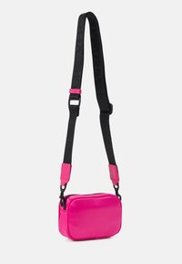 Rosa rektangulär väska i glänsande material med dragkedjestängning. Har en svart justerbar rem med Versace-logotyp och rosa detaljer.