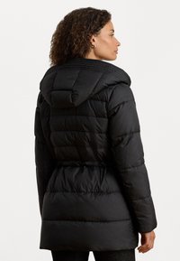 Μαύρο φούτερ μπουφάν με κουκούλα, ραφή με κέντημα, στενόμεση μέση και λεία υφή. Το μπουφάν έχει μεσαίου μήκους κοπή και μακριά μανίκια.