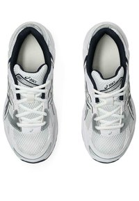 Valkoiset urheilukengät, joissa on verkkomateriaali, hopeiset yksityiskohdat, mustat yksityiskohdat ja nauhat. Varustettu pyöreällä kärjellä ja pehmustetulla pohjalla mukavuutta varten.