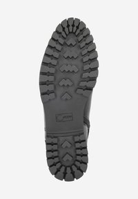 Black rubber boot sole with deep, zigzag tread pattern and brand logo. Features raised traction elements for improved grip and stability.