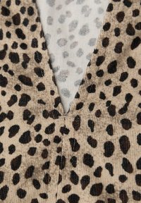 Leopardmønstret stof med en tekstureret, corduroy-finish i beige og brun, med en V-udskæring og synlige sømme.