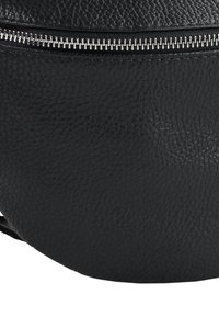 Sac à dos en cuir noir à surface texturée, forme circulaire et détail de fermeture éclair en métal. Équipé d'une sangle ajustable pour un port polyvalent.