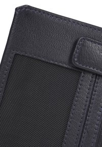 Cartera de cuero azul marino con acabado texturizado, panel de malla y costuras en contraste. Presenta un cierre de solapa y bordes pulidos.
