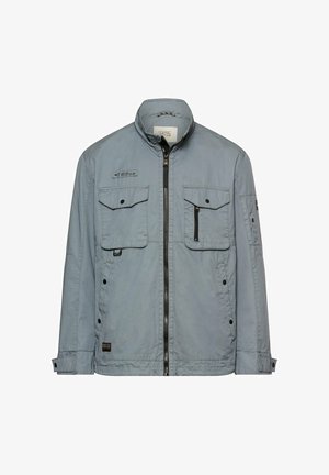 Veste grise claire pour homme avec fermeture éclair à l'avant, deux poches poitrine à boutons, une poche zippée et des poignets de manche réglables.