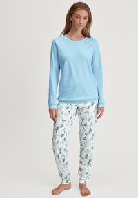 Lichtblauw longsleeve pyjamashirt gecombineerd met witte broeken met een herhaald zwart en blauw dieren- en objectenprint. Zachte stof, casual pasvorm.