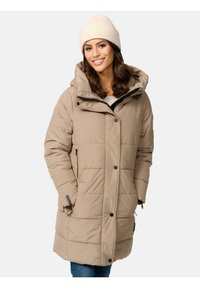 Beige pufferjack met een capuchon, voorzien van horizontale stiksels, zwarte ritsaccenten en knopen. Gebreide crèmekleurige muts op het model.