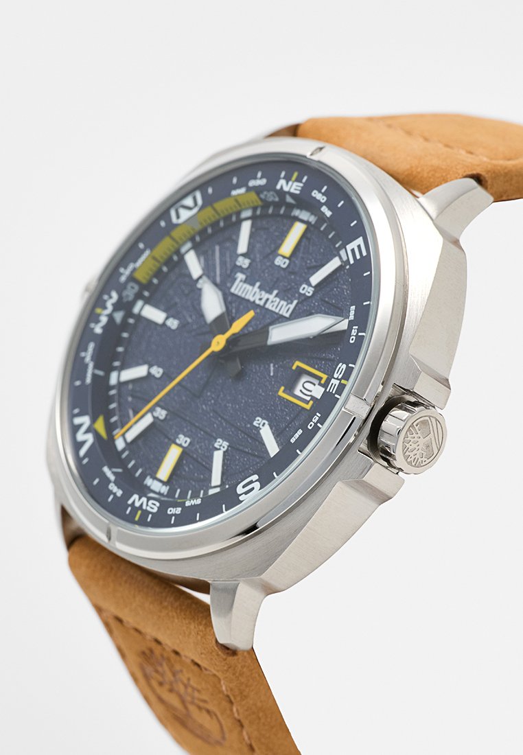 Analoge Timberland horloge met zilveren kast, zwarte wijzerplaat, gele en witte markeringen, datumaanduiding, en een bruine leren band met reliëflogo.