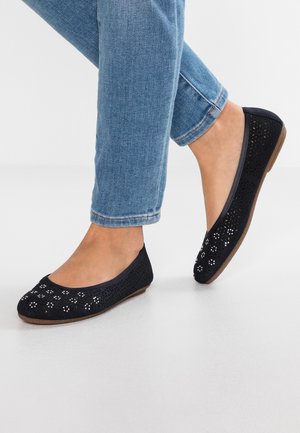 Sateen sininen tasapohjainen kenkä, jossa on leikattuja kukkakuvioita, pyöreä kärki ja matala ruskea pohja. Yhdistetty vaaleansinisiin nilkkapituisiksi farkkushortseihin.