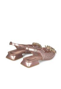 Chaussures en tissu tissé couleur or rose avec un talon carré. Présentent des accents floraux sur le devant et une sangle de cheville ajustable. Semelle plate.