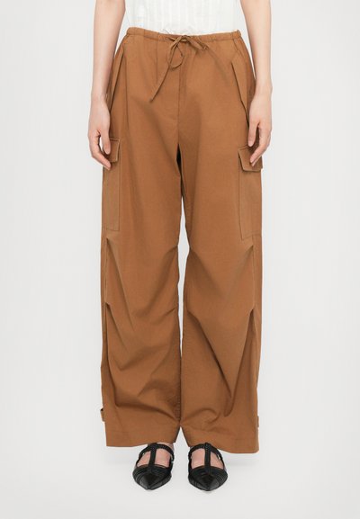 Pantalons cargo marron à jambes larges avec taille élastique, cordon de serrage et poches latérales, fabriqués à partir d'un tissu lisse et léger.