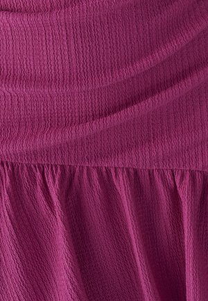 Fuksjowy materiał o fakturze, z pofałdowanym wzorem, zebranym dołem i gładką górną częścią. Miękki, układający się materiał.