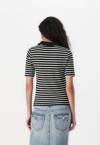 Svart og hvitstripet t-skjorte med korte ermer og en teksturert strikkedesign, kombinert med et blått denimskjørt som har baklommer.