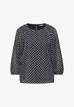 Vzdušná námořnická halenka s bílým geometrickým vzorem, kulatým výstřihem a průhlednými rukávy. Má neprůhledné tělo a diskrétní zapínání na zadní straně.