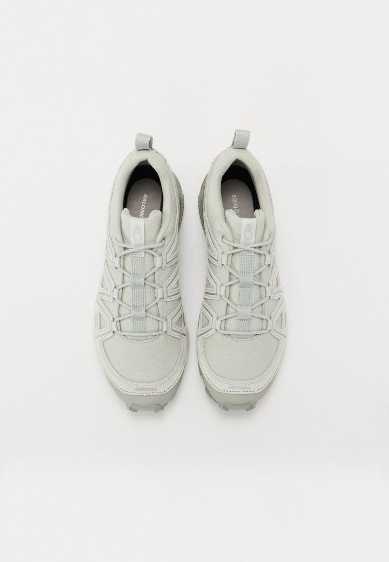 Zapatillas deportivas de color gris claro con parte superior de malla texturizada, puntera reforzada, cordones elásticos y suelas de goma con dibujos antideslizantes.