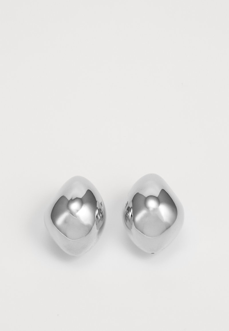 Ασημένια μεταλλικά σκουλαρίκια με απλή, στρογγυλή μορφή, που διαθέτουν γυαλιστερή επιφάνεια και ανακλαστική επιφάνεια. Μινιμαλιστικός σχεδιασμός χωρίς διακοσμήσεις.