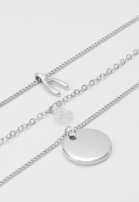 Sidabriniai sluoksniuoti kaklo papuošalai su U formos pakabuku, skaidriu kristalo žavesiu ir apvaliu lygiu diskiniu pakabuku.