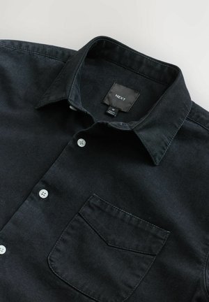 Zwarte denim overhemd met een kraag, voorzien van een voorzak, witte knopen en een label gemarkeerd met "NEXT" in maat medium.