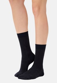 Calze nere a motivi caratterizzate da una trama testurizzata, bordo a costine e tallone rinforzato, che offrono una vestibilità aderente e un materiale flessibile.