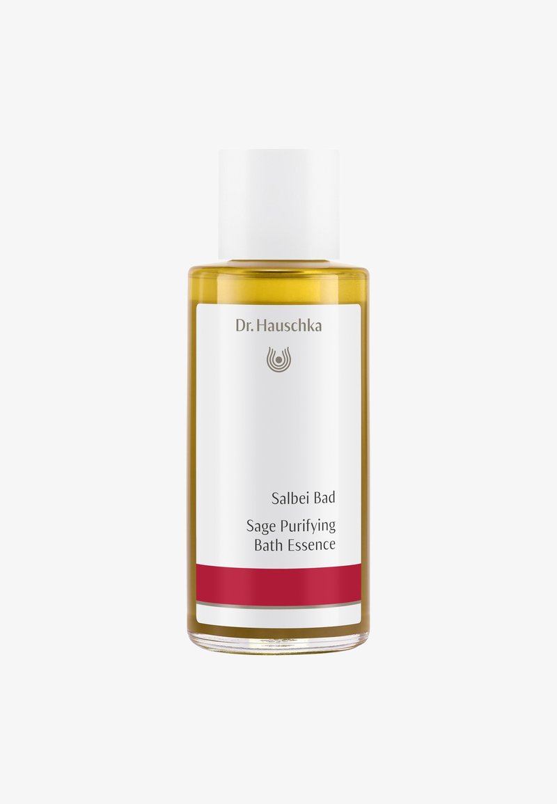 Bouteille en verre transparent contenant un liquide doré, avec un capuchon blanc et une étiquette présentant le nom de la marque, le titre du produit et une bande d'accent rouge.