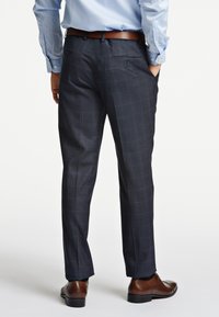 Pantaloni a quadri scuri con vestibilità su misura, realizzati in un elegante misto lana texturizzato. Finiti con tasche posteriori e abbinati a scarpe eleganti marroni.