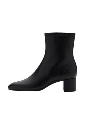 Botín de cuero negro hasta el tobillo con punta afilada y tacón rectangular. Superficie lisa con un sutil detalle de costura alrededor del borde superior.