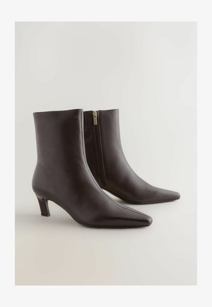 Black leather ankle boots with a pointed toe and a block heel. Features an inner side zipper for easy wear, smooth texture, and sleek design.