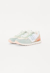 Baskets de sport vert clair et beige avec des accents blancs, en matières suédées et synthétiques, lacets texturés et semelle en caoutchouc rose.