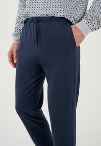 Pantaloni jogger blu navy realizzati in tessuto morbido, con vita elasticizzata e cordino regolabile. Presentano tasche laterali e un design affusolato.