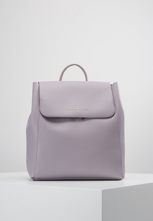Sac à dos en cuir violet avec une surface texturée, un rabat repliable et un logo doré. Il dispose d'une poignée supérieure et de côtés robustes.