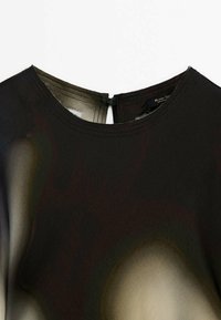 Blouse en satin noir avec col rond et petite fermeture boutonnée au dos, présentant une texture de tissu lisse et légèrement réfléchissante.