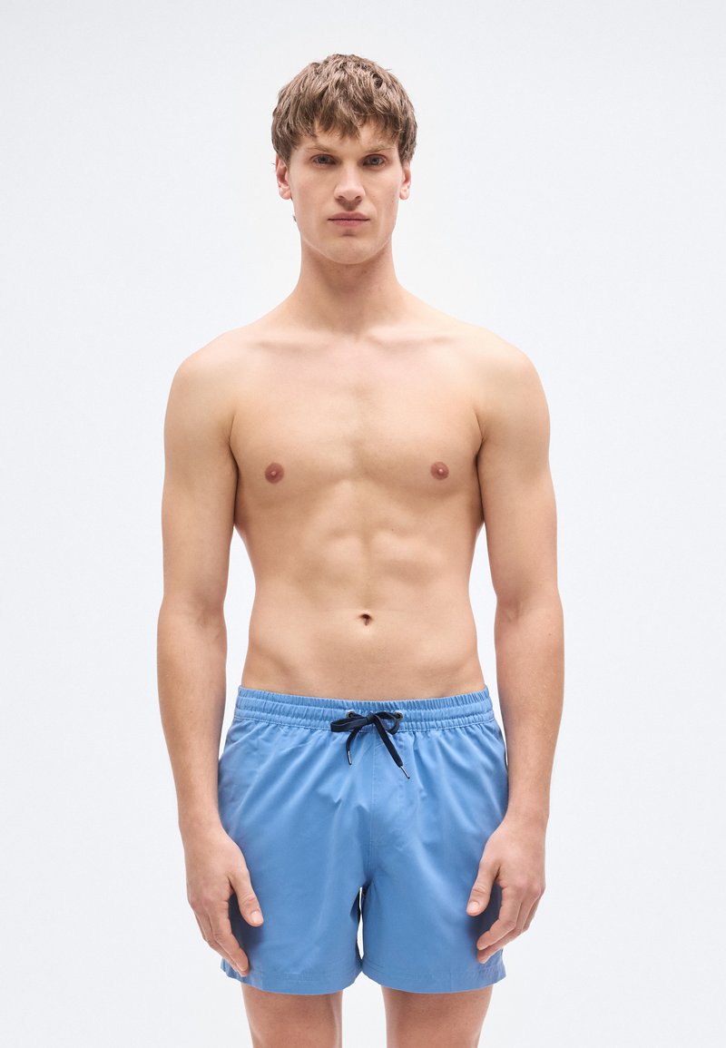 Μπλε μαγιό σορτς από ελαφρύ ύφασμα, με ελαστική μέση και μαύρο κορδόνι, που φτάνει πάνω από τα γόνατα με ομαλή υφή.